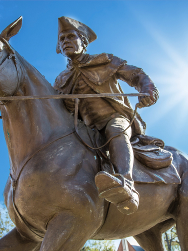 Looking up at a statue of Captain jack on a horse with the blue sky in the background.